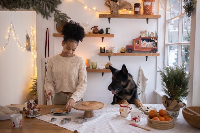 Woman putting Christmas cookies on a tray and her dog watching her